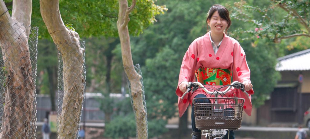 A woman wearing a kimono is riding a bicycle